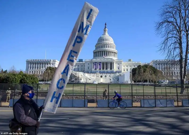 un manifestante con uno striscione per l impeachment a trump 