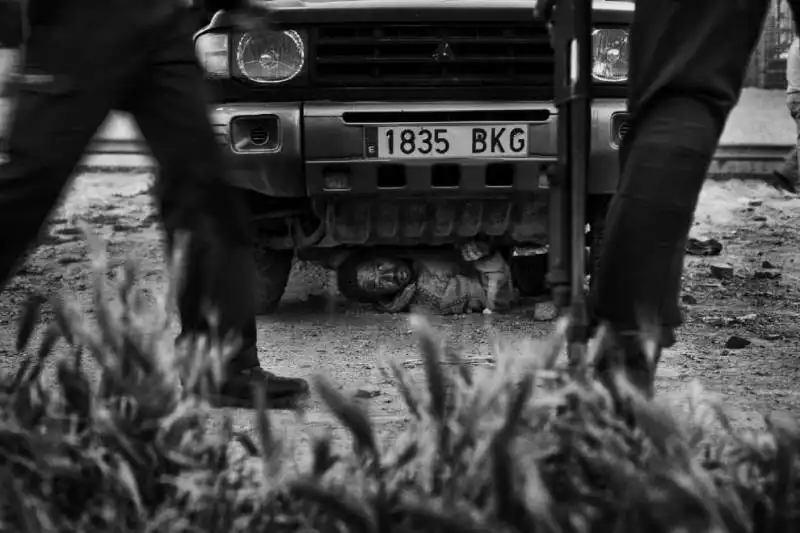 migrante nascosto sotto un'auto tripodo