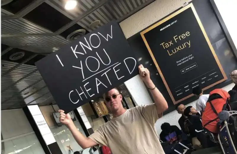 RAGAZZO ASPETTA LA FIDANZATA ALL'AEROPORTO DI MELBOURNE CON UN CARTELLO CON SCRITTO 'SO CHE MI HAI TRADITO'