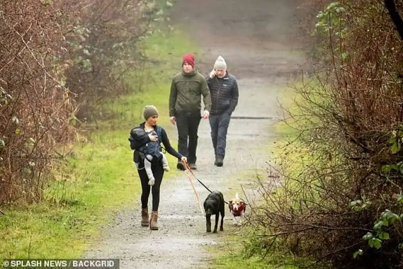 meghan passeggia con archie e i cani e dietro due uomini della sicurezza canadese