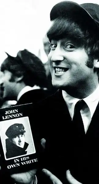 JOHN LENNON MOSTRA UNA COPIA DEL SUO LIBRO 