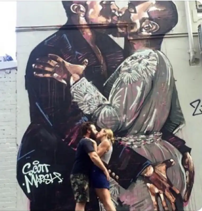 le coppie si baciano sotto il murale di kanye west