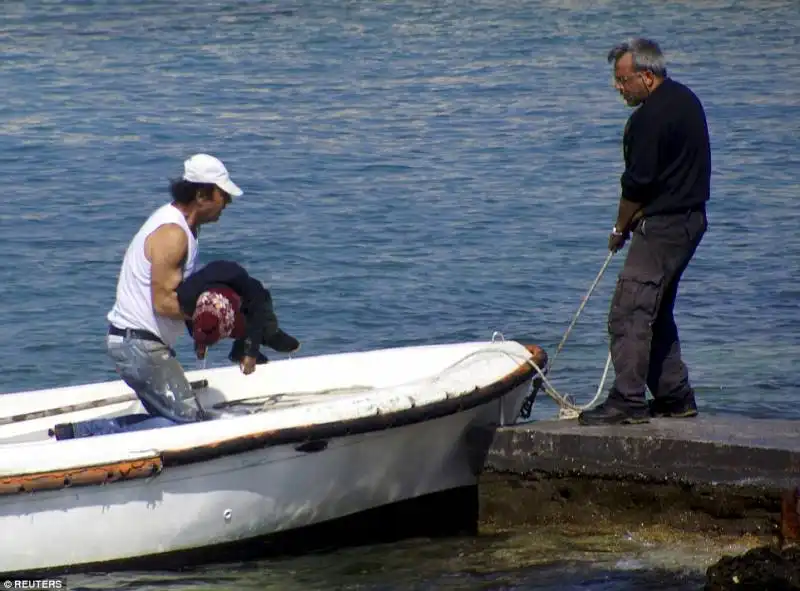 il cadavere di un bambino trasportato a riva dai soccorritori di rodi