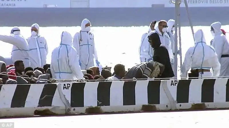 migranti    naufragio nel canale di sicilia   relief workers stand around a group of migrants as they wait to  a 12 1429476904687