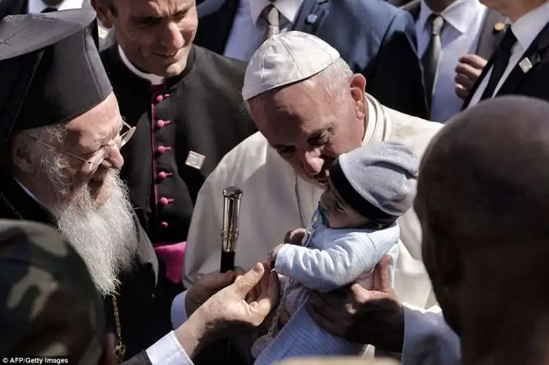 papa francesco con il patriarca bartolomeo e un bimbo rifugiato