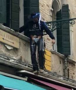 TURISTA VESTITO DA COWBOY CAMMINA SU UN CORNICIONE A VENEZIA