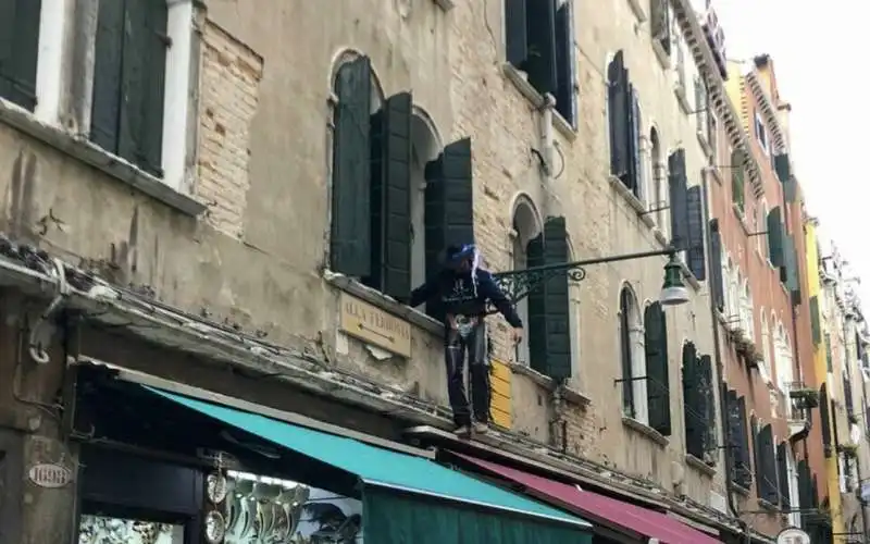 TURISTA VESTITO DA COWBOY CAMMINA SU UN CORNICIONE A VENEZIA