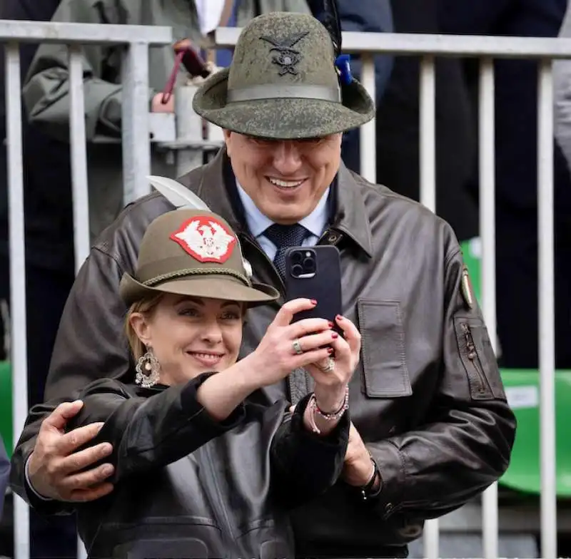 giorgia meloni e guido crosetto con il cappello degli alpini a udine 