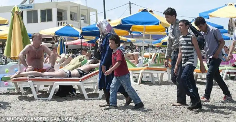 migranti in spiaggia coi turisti