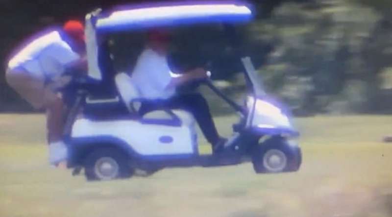 donald trump sulla golf car con il caddy aggrappato sul retro