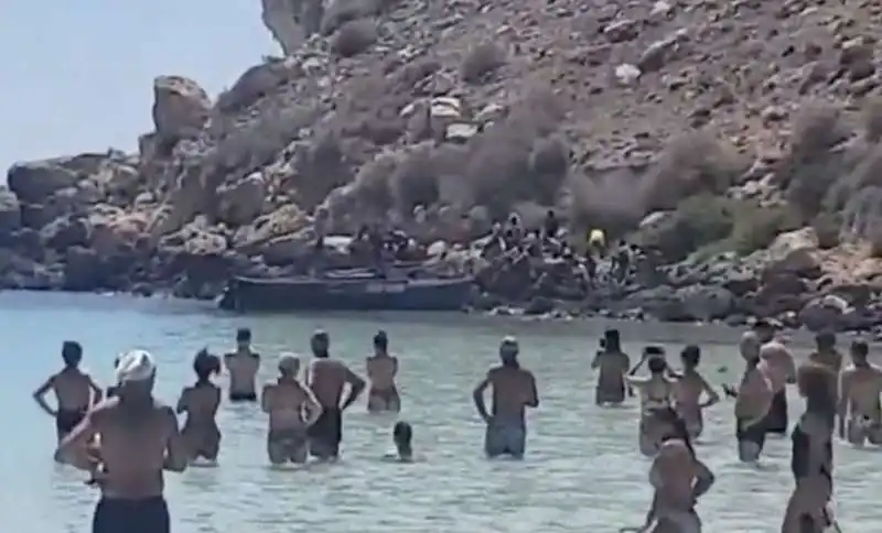 migranti sbarcano sull'isola dei conigli a lampedusa in mezzo ai turisti 2