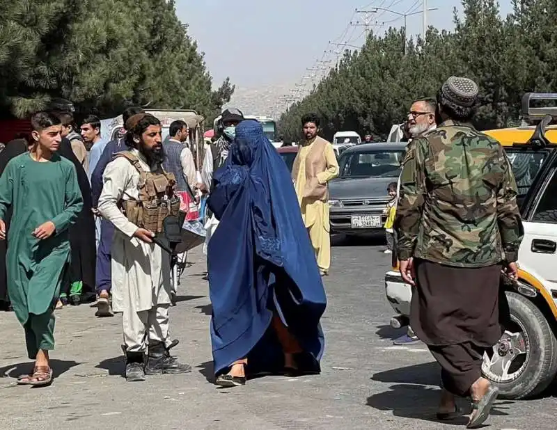 donna con il burqa in mezzo ai talebani che bloccano le strade per l aeroporto di kabul 