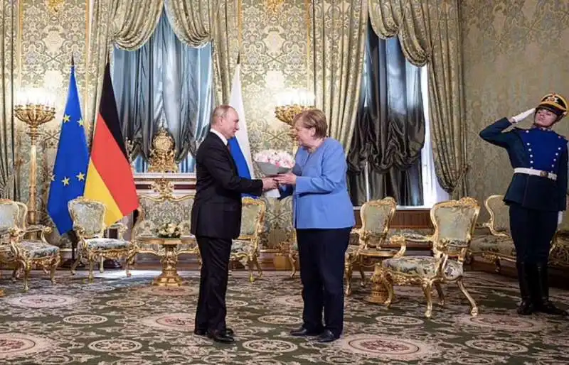 vladiimir putin dona un mazzo di fiori ad angela merkel