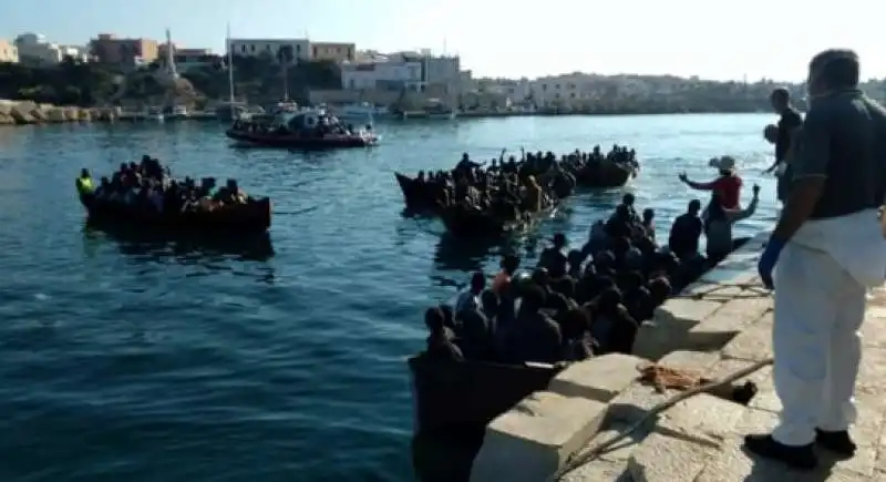 fila di barchini carichi di migranti al molo di lampedusa 1