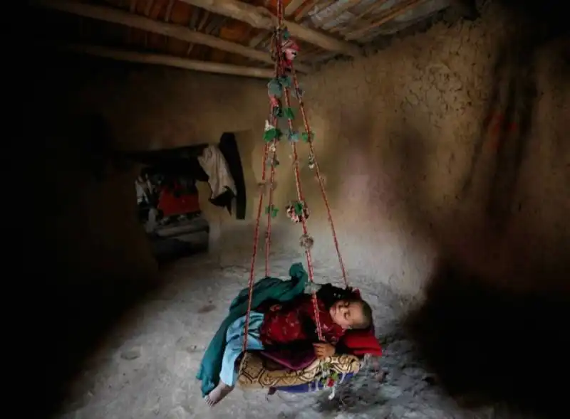 un bambino afghano dorme in un campo profughi a kabul