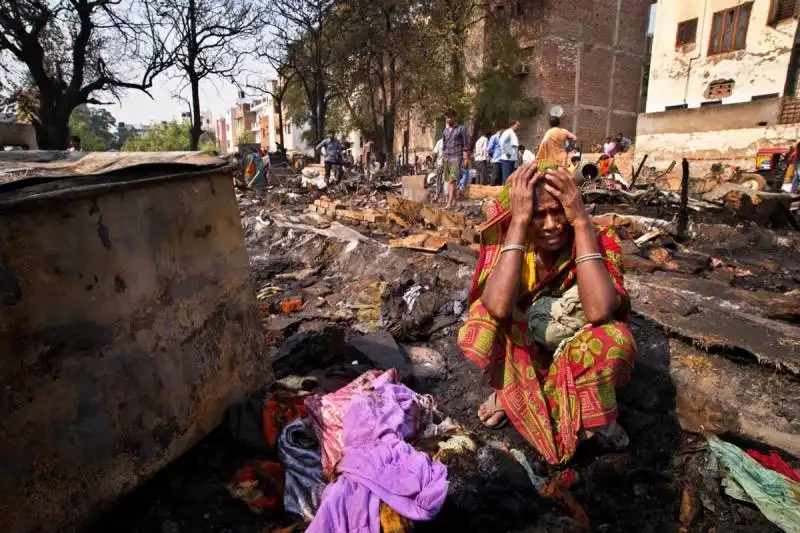 una donna piange un pacco di soldi bruciati dopo un incendio in india