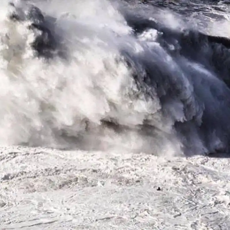 un puntino di surfista al cospetto delle onde