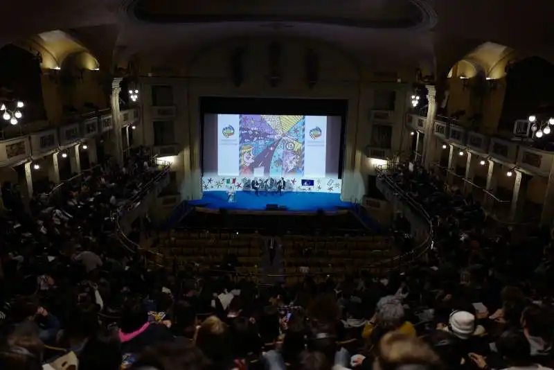 il palco con i relatori e la sala del teatro odeon con gli studenti