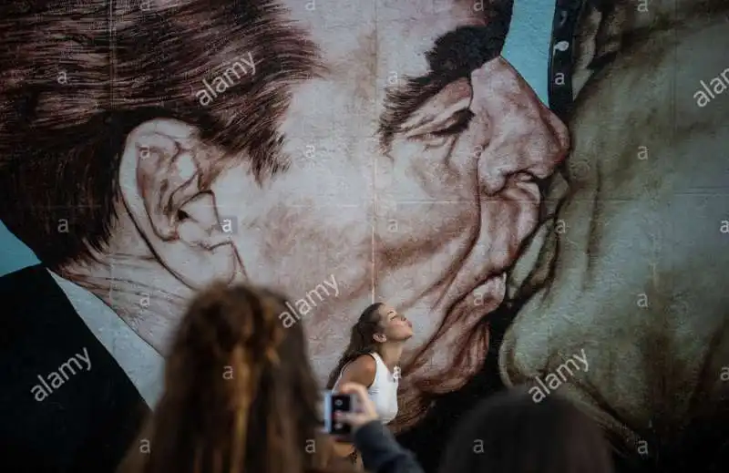 una ragazza tira un bacio di fronte al murale the mortal kiss