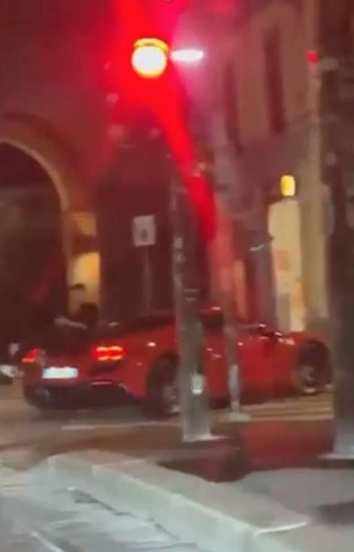 milano ragazzo parla al telefono seduto sul cofano posteriore della ferrari 2