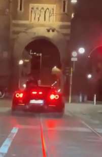 milano ragazzo parla al telefono seduto sul cofano posteriore della ferrari 3