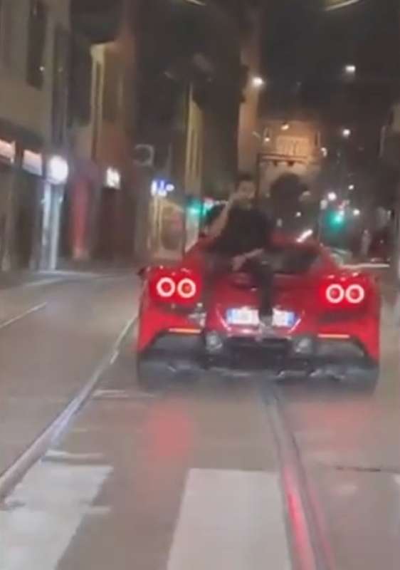 milano ragazzo parla al telefono seduto sul cofano posteriore della ferrari 5