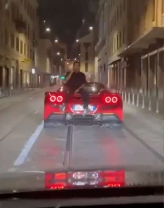 milano ragazzo parla al telefono seduto sul cofano posteriore della ferrari 6