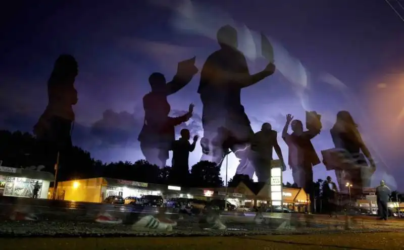 protesters march in the street as lightning flashes in the distance in ferguson