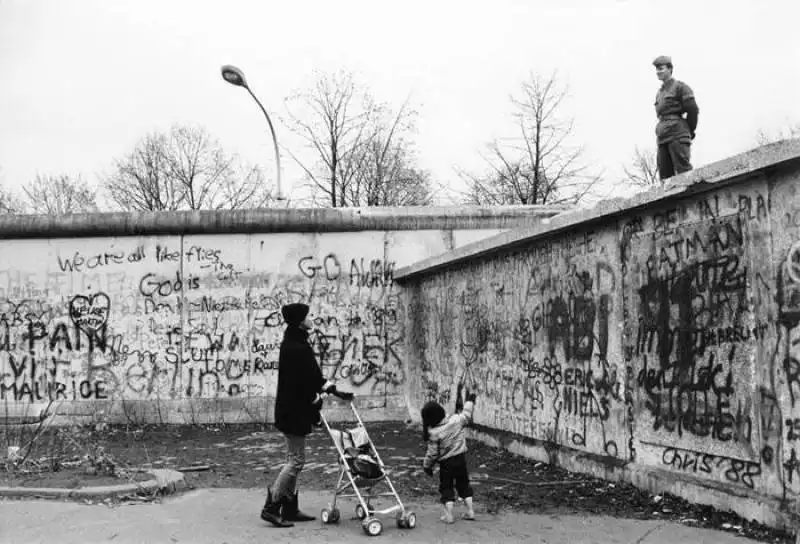 uninsolita conversazione fra cittadini  la giovane mamma che vive allovest e il soldato guardia di frontiera della repubblica democratica tedesca, berlino, 1989 mario dondero