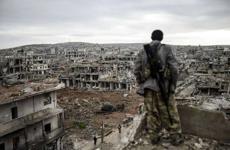 un soldato curdo guarda kobane distrutta