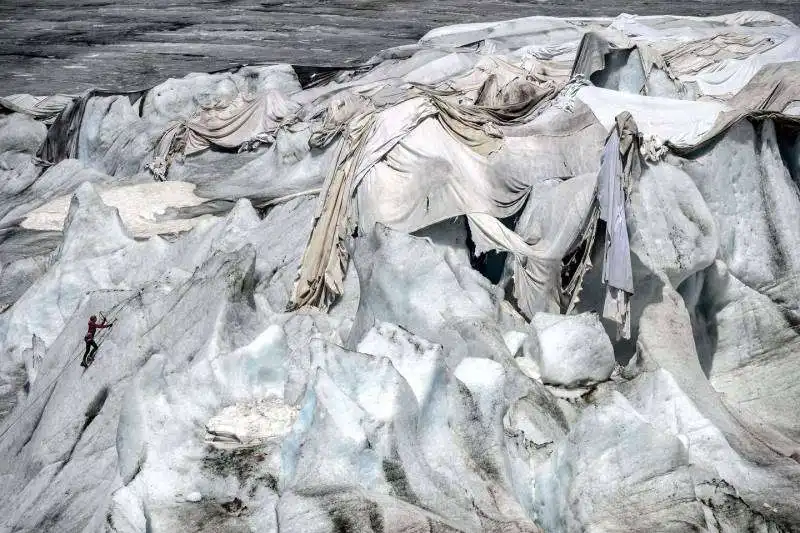 una donna scala un muro bianco sul ghiacciaio del rodano in svizzera