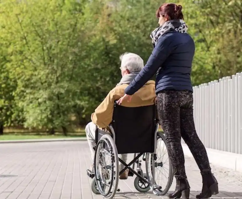 badante con uomo in sedia a rotelle disabile